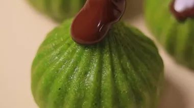 Pistachio modaks drizzled with melted chocolate on a festive plate 4